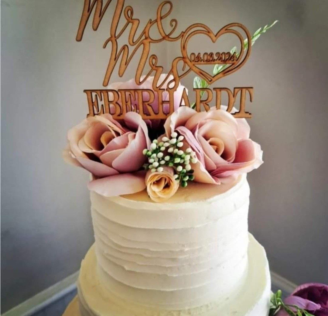 A white celebration cake decorated with pink sugar flowers