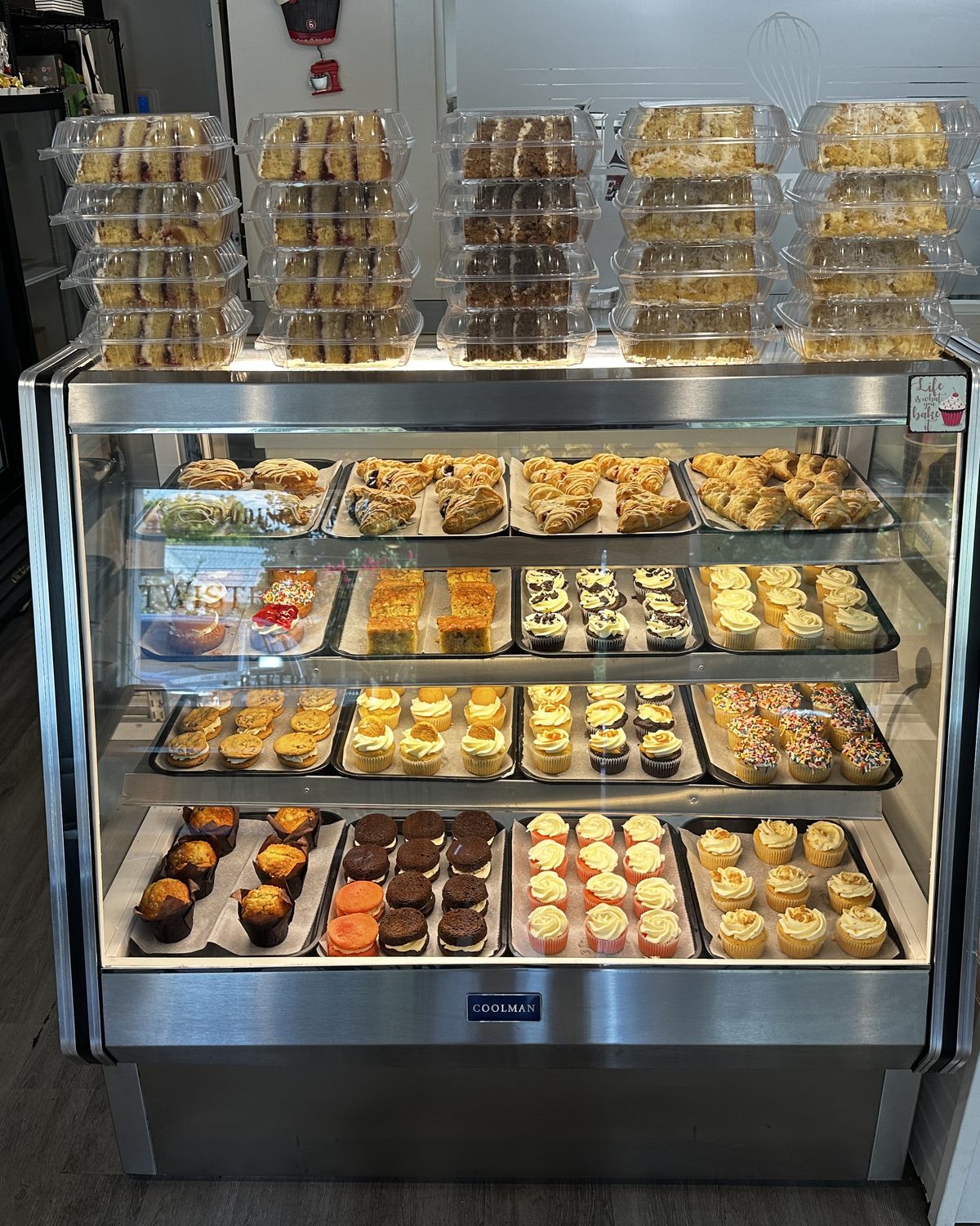 The Twisted Whisk display case stacked with fresh cupcakes, bars and pastries